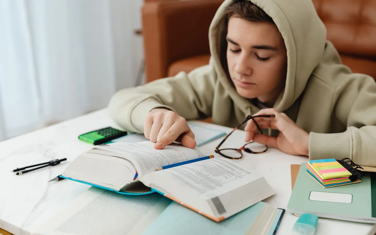 Kitap okuyarak çalışan kapüşonlu bir genç