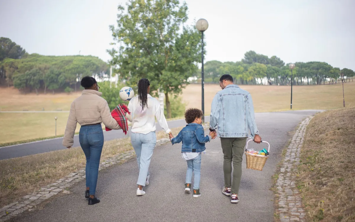 Piknik sepetiyle parkta yürüyen bir aile